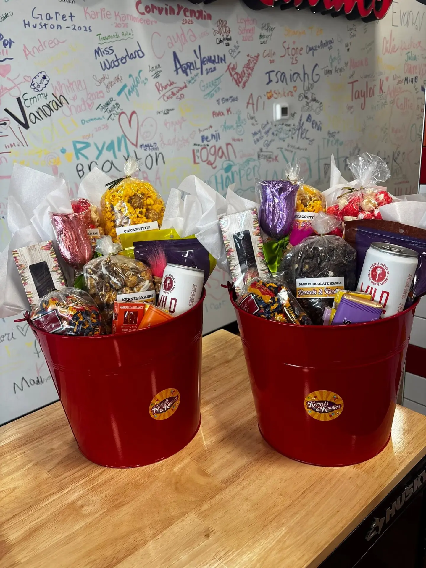 Two red Kernels & Kandies gift buckets filled with popcorn and candy