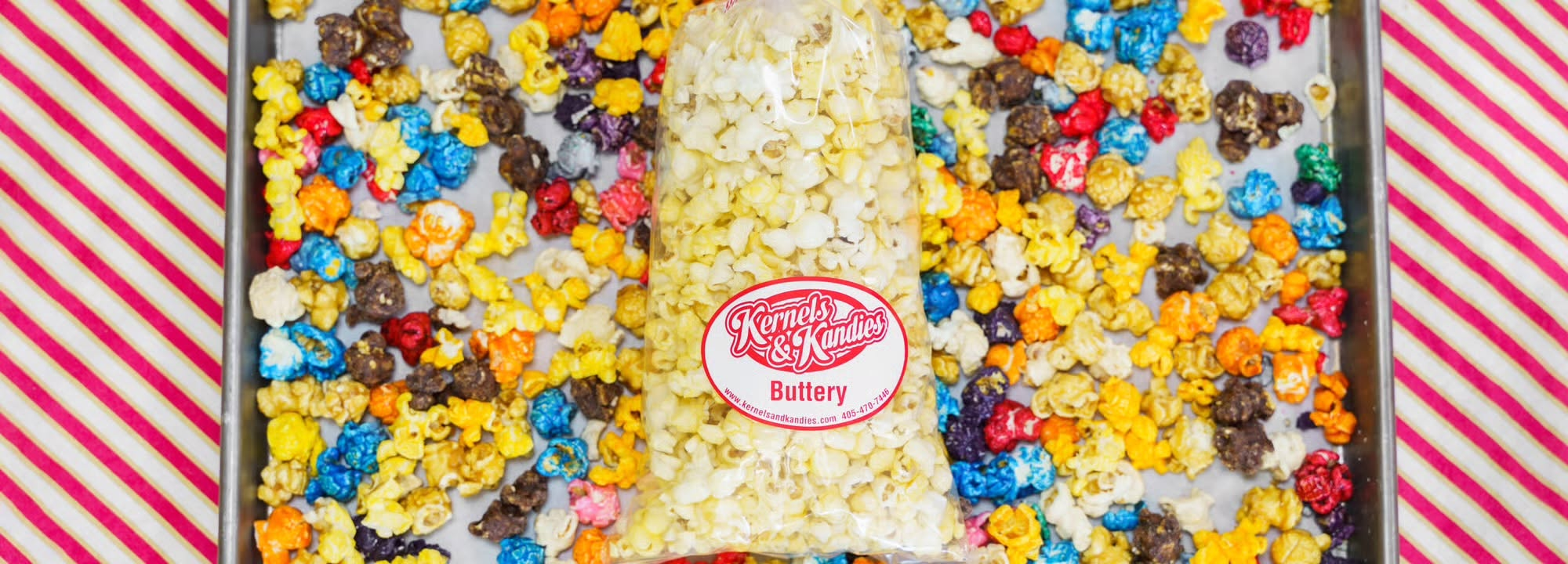 Tray of rainbow candied popcorn with a bag of buttery kettle corn